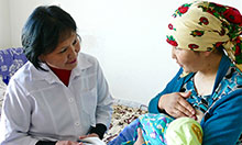 Healthcare worker working with mother holding infant