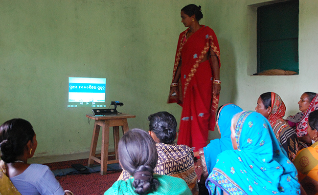 Photo of a group of women watching a video on a wall inside