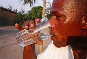Photo of a man drinking water outside.