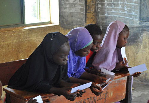 Three Nigerian school girls look at information.
