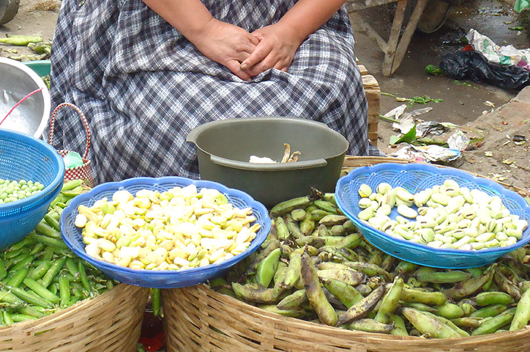 Photo of a woman selling produce at a market.