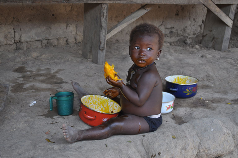 Photo of a child eating on the ground.