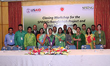 Closeout workshop participants standing in front of a SPRING/Bangladesh banner.