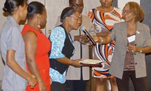 Nicole Racine, SPRING/Haiti country manager handing the microphone to Center Nutrition Focal Point, Miss Ninette Dupuy with Trainers from Hopital Ste Therese de Hinche at the closing ceremony on October 13, 2015.