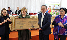 Photo of the group at the BFHI awards ceremony, four people smile and pose holding a large plaque. Caption: At-Bashy FMC is awarded BFHI certification. (pictured left to right) Jarkyn  Ibraeva, Deputy Governor of Naryn oblast, Nurgul Ibraeva Senior Specialist of MOH, Nurdin Aliev Director of At-Bashy FMC, and Sadat Sattarova Head of Save the Children International Kyrgyzstan office.