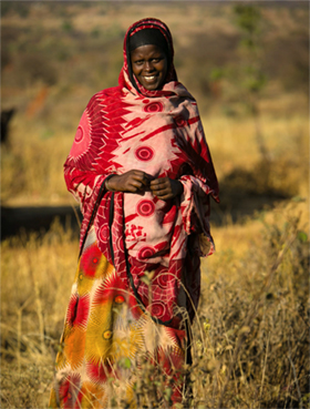 Photo of a woman smiling while standing in a field