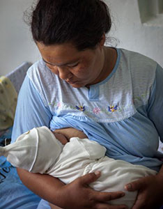 A woman holds and breastfeeds her infant.