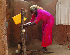 Photo of a woman smiling as she uses a tippy tap.