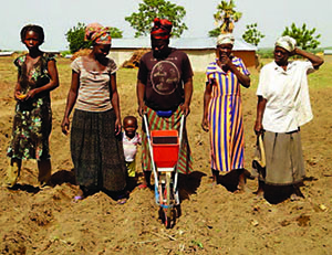 Photo of a group of women and a child posing in the field they are working.