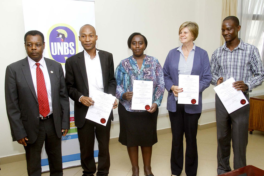 During a laboratory recognition ceremony, representatives of accredited laboratories pose with their certificates of recognition with Ben Manyindo (far left), the executive director of UNBS.