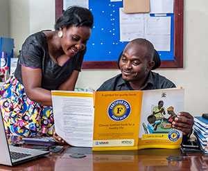 Abdul Nuldin Katongole and Jolly Ruyonga, traders who work with maize millers, read a factsheet on food fortification.
