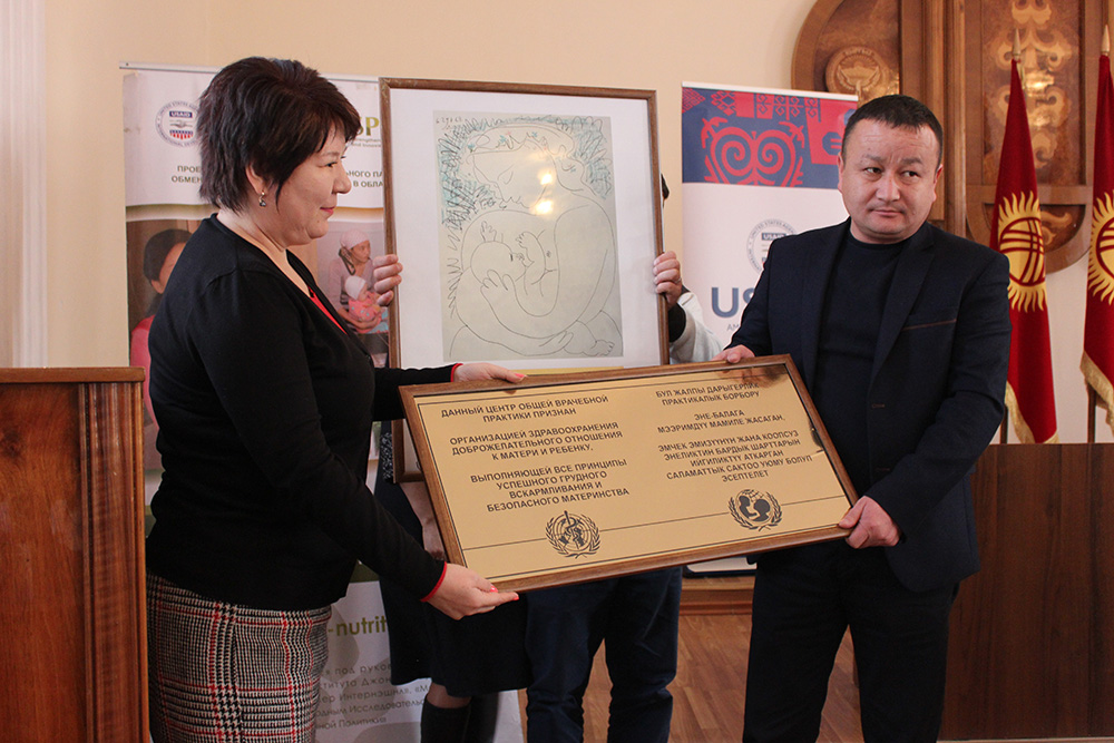 USAID Health Project Management Specialist Aisha Zhorobekova presents the BFHI certification plaque to Abdulbaki Yrysbekov, Director of Karakul General Medicine Practice Center in Jalalabad oblast.