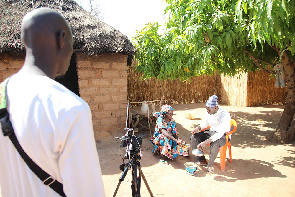 Two community members being filmed eating a delicious meal containing orange-fleshed sweet potato.