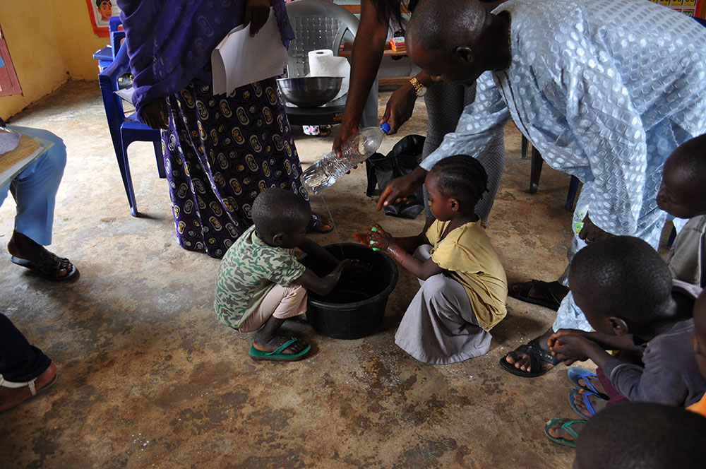 Children aged 2-5 practice handwashing with a tippy tap during concept testing for nutrition and hygiene activities included in a training package geared towards OVCs.