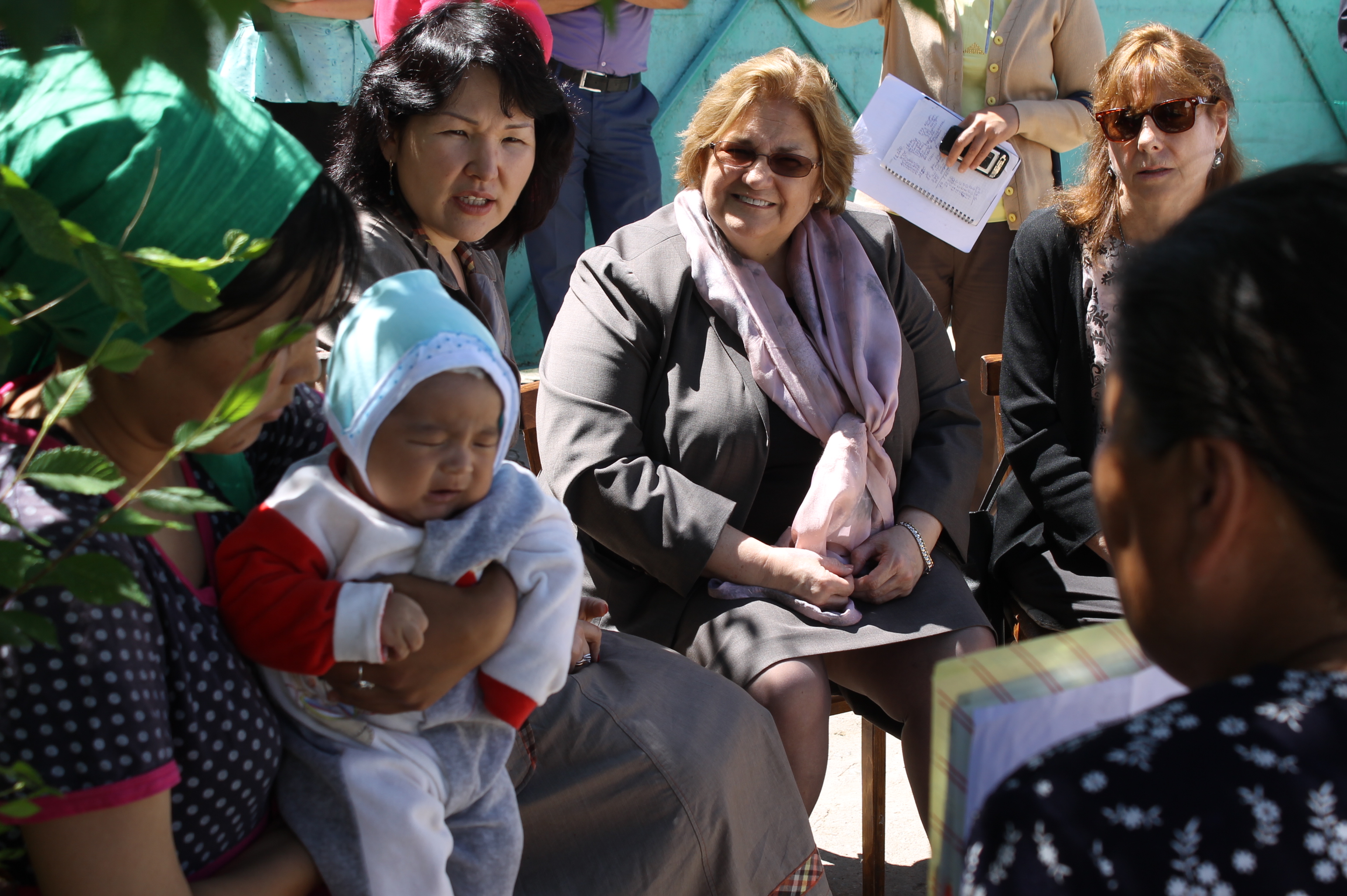 Ambassador Gwaltney watches as SPRING volunteers talk to new mother at her home about the importance of exclusive breastfeeding for the first six months of her child’s life.