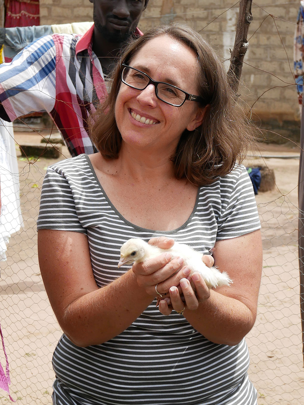 USAID Senegal Agriculture/Nutrition specialist, Megan Kyles, holds a baby turkey from one of the improved village poultry coops.