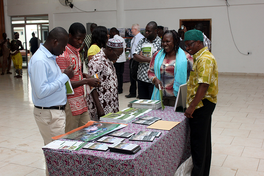 Ziba Dokurugu, SPRING’s Agriculture Advisor, receives visitors admiring SPRING’s aflatoxin training manuals on display at the event.