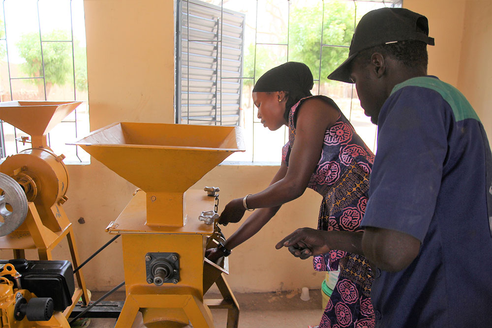 A technician from Hydro Bati Mec (HBM), the farming equipment company that supplied the processors, teaches a participant how to use it.
