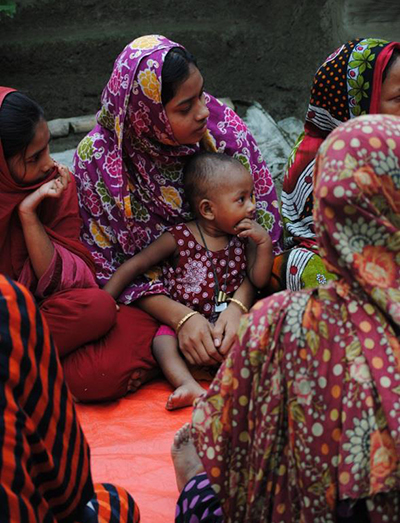 Photo of a mother holding her child close as they sit in a group looking up at a FNS session.