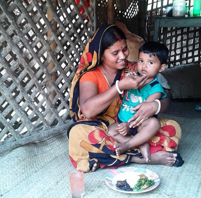 Photo of a woman feeding her child from a plate set before them. 