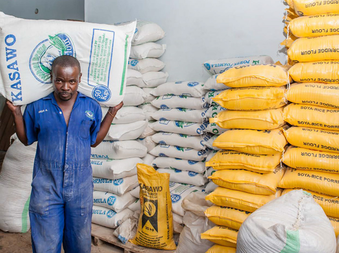 Maize mill employee Haruna Ssemakula carries a sack of maize flour to a waiting truck.