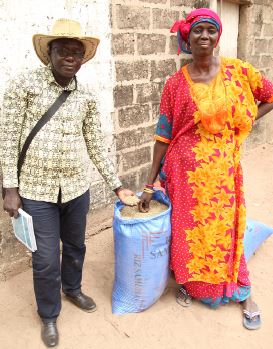 Thiane shows off a bag of bio-fortified millet that she grew with support from SPRING Agriculture Advisor, Aliou Babou.