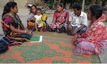 Union Facilitator Oloka Biswas speaks to a farmer nutrition school graduate and her family members.