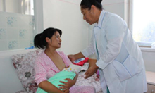 Photo of a woman holding a newborn with a midwife advising