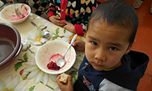 Photo of a young boy with a bowl of food on the table in front of him. Caption: "The beet salad is a hit at lunch time!"