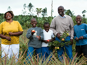 Photo of adults and children holding produce and smiling. USAID/Morgana Wingard