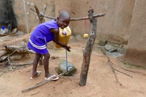 A young girl uses a tippy-tap to wash her hands.