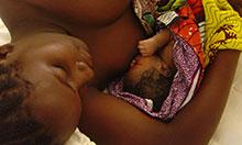 Overhead view of a woman lying down and breastfeeding her infant