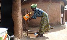 Photo of a woman washing her hands at a tippy-tap. 