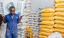 Maize mill employee Haruna Ssemakula carries a sack of maize flour to a waiting truck.