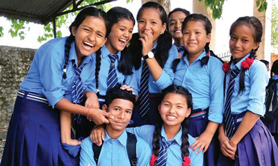 Photo of a group of adolescents smiling and huddling together to pose. 