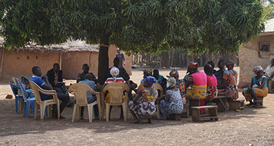 Photo of a counseling group meting in a circle under a large tree. 