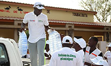 SPRING/Senegal SBCC Advisor Albert Boubane, standing in the bed of a truck, distributes water to participants before the hike.