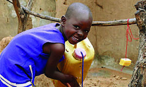 A young girl washes her hands at a tippy tap.